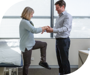 Dr Adam Woodbridge or specialist assisting with knee rehabilitation exercise for work-related injury recovery